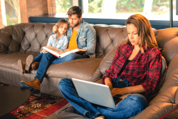 WOman-working-on-laptop-while-family-plays