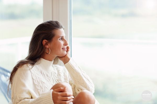 woman looking out the window looking content and fulfilled.