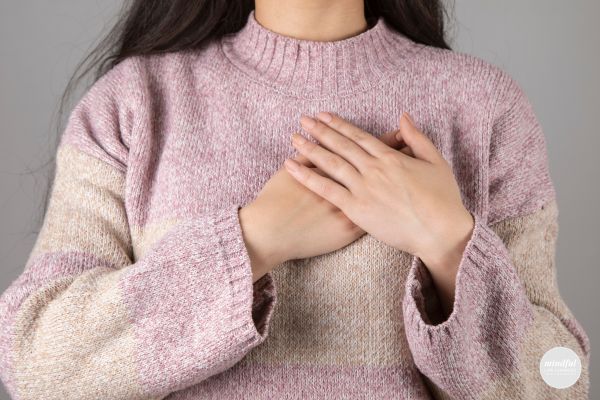 middle-age woman placing hand over heart for gratitude affirmation.