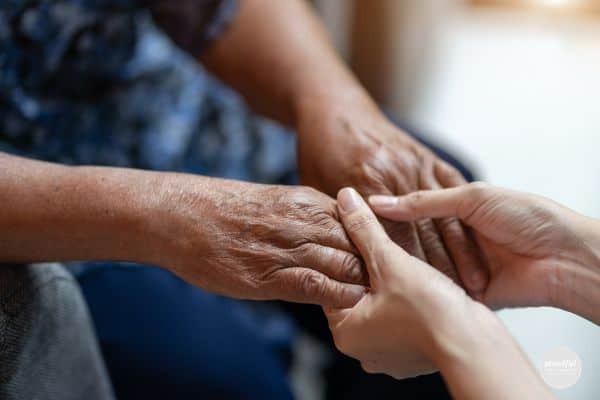 middle age woman holding eldery father's hands