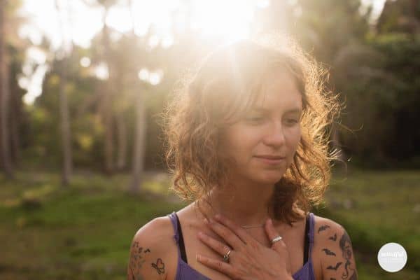 woman in nature with her hand over her heart.