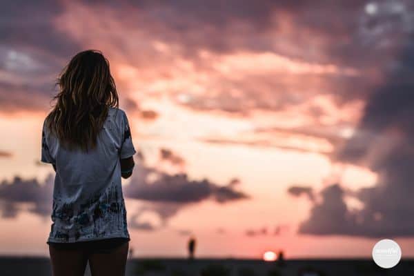 Woman looking out at the cloudy sunset