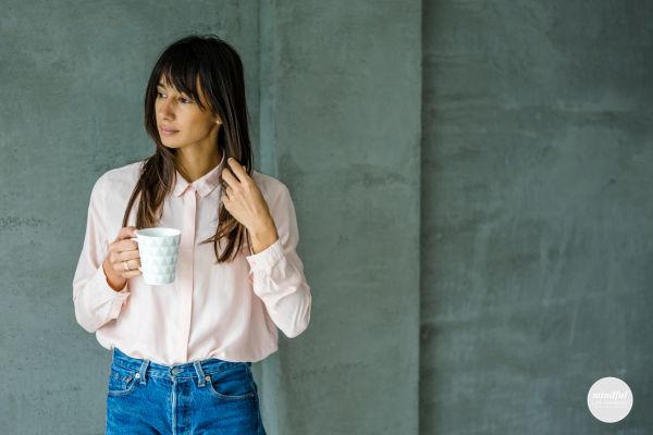 Woman drinking coffee, contemplating about her layoff.