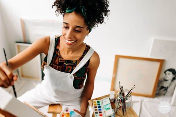 middle-age woman happily painting, adding play back into her life.