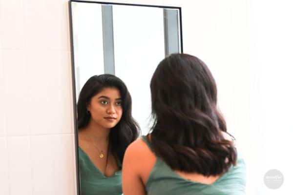 A woman looking in the mirror, and loving the way she looks and feels with affirmations